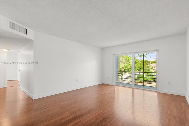 empty room with hardwood / wood-style floors and a textured ceiling