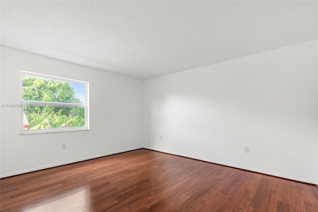 unfurnished room featuring wood-type flooring and a textured ceiling