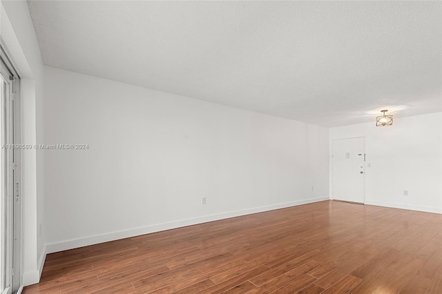 spare room with a textured ceiling and hardwood / wood-style flooring