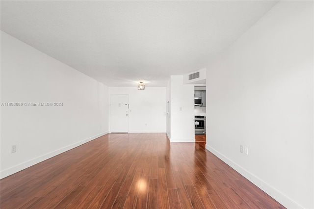 empty room with a textured ceiling and dark hardwood / wood-style floors