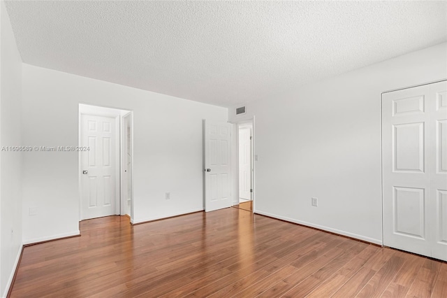 unfurnished room with hardwood / wood-style floors and a textured ceiling