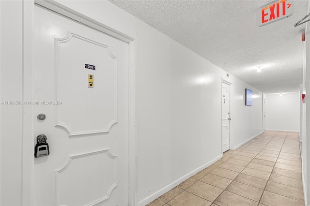 hallway featuring light tile patterned flooring and a textured ceiling