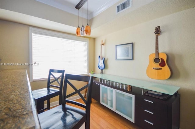 kitchen with pendant lighting, light wood-type flooring, and crown molding