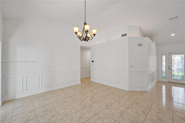 empty room with a chandelier, light tile patterned floors, and vaulted ceiling