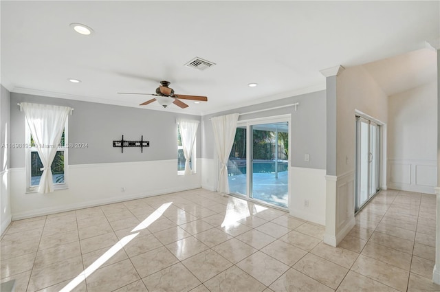 tiled empty room with ceiling fan and ornamental molding