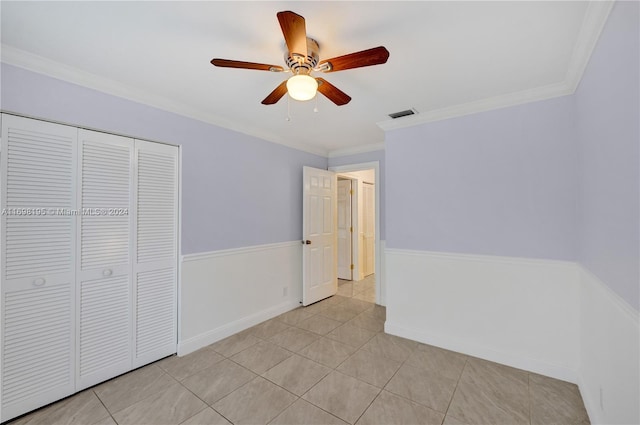 unfurnished bedroom featuring ceiling fan, ornamental molding, light tile patterned floors, and a closet