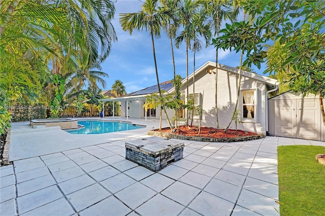 view of pool with a storage shed, an in ground hot tub, and a patio