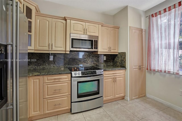 kitchen with backsplash, dark stone countertops, light tile patterned flooring, appliances with stainless steel finishes, and light brown cabinetry