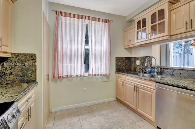 kitchen featuring dark stone counters, sink, stainless steel appliances, and light tile patterned flooring