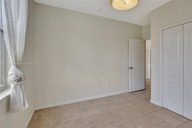 unfurnished bedroom featuring light tile patterned floors and a closet