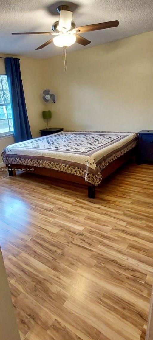 unfurnished bedroom with ceiling fan, a textured ceiling, and light hardwood / wood-style flooring