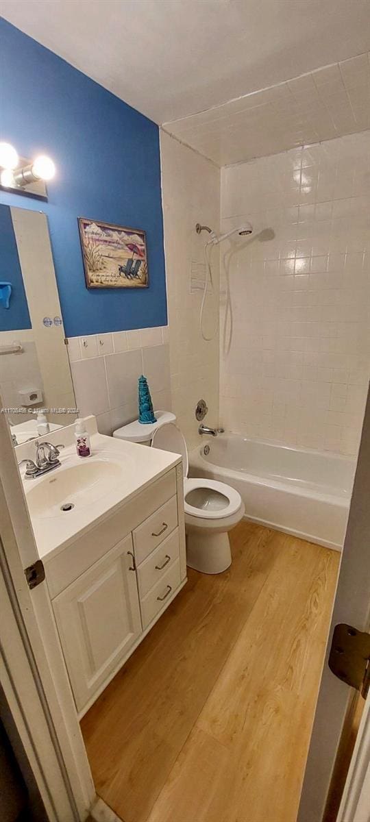 full bathroom with vanity, wood-type flooring, tiled shower / bath combo, and toilet