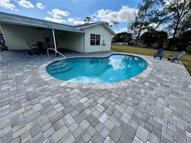 view of swimming pool with a yard, ceiling fan, and a patio area