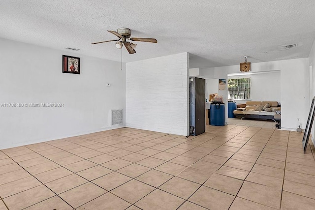 spare room with ceiling fan, light tile patterned floors, and a textured ceiling