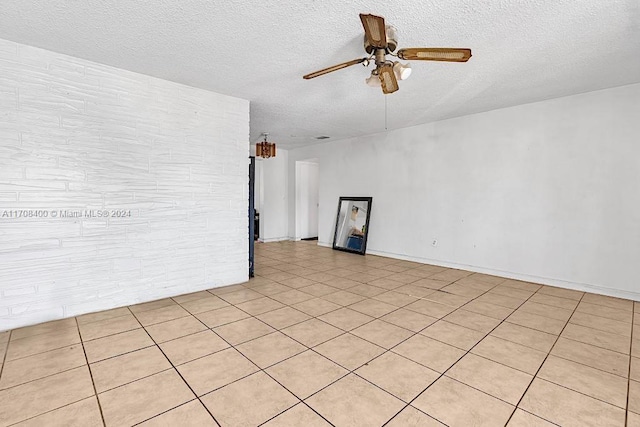 spare room featuring ceiling fan, light tile patterned floors, and a textured ceiling