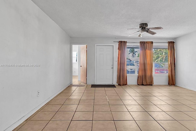 tiled empty room with ceiling fan and a textured ceiling