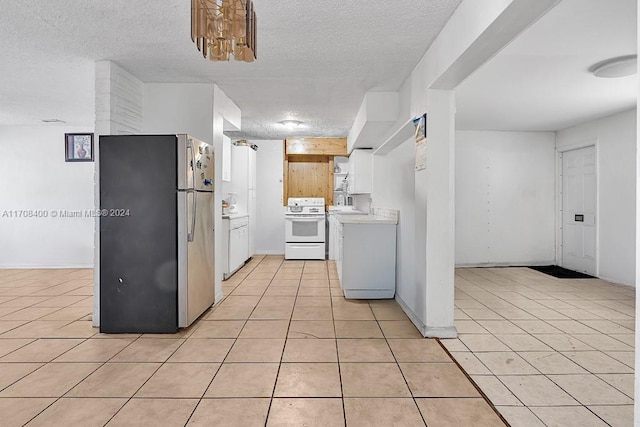 kitchen with white cabinets, white range oven, light tile patterned floors, and stainless steel refrigerator