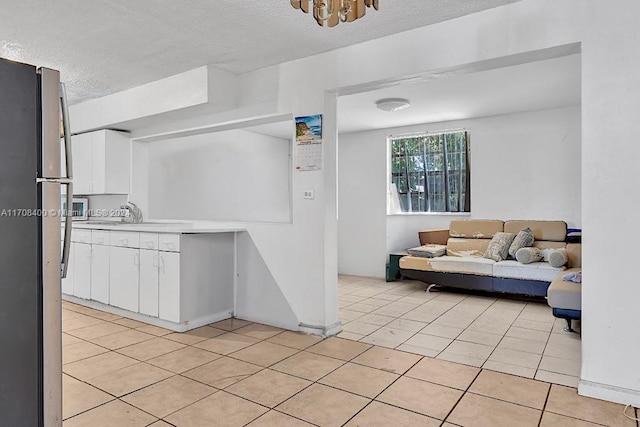 kitchen featuring light tile patterned flooring, white cabinetry, a textured ceiling, and appliances with stainless steel finishes