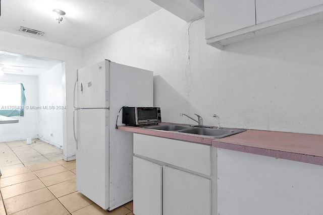 kitchen featuring white refrigerator, light tile patterned floors, and sink