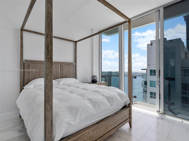 bedroom with access to exterior, a water view, and a wall of windows