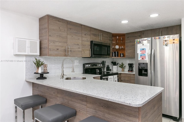 kitchen with a breakfast bar, kitchen peninsula, sink, and appliances with stainless steel finishes