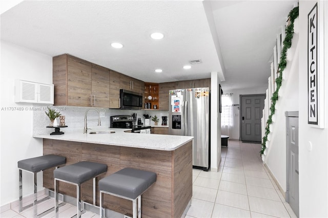 kitchen featuring a breakfast bar, sink, tasteful backsplash, kitchen peninsula, and stainless steel appliances