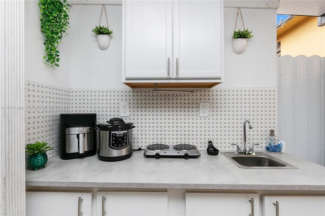 kitchen featuring backsplash, sink, and white cabinets