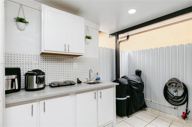 kitchen featuring white cabinetry, sink, light tile patterned floors, and tasteful backsplash