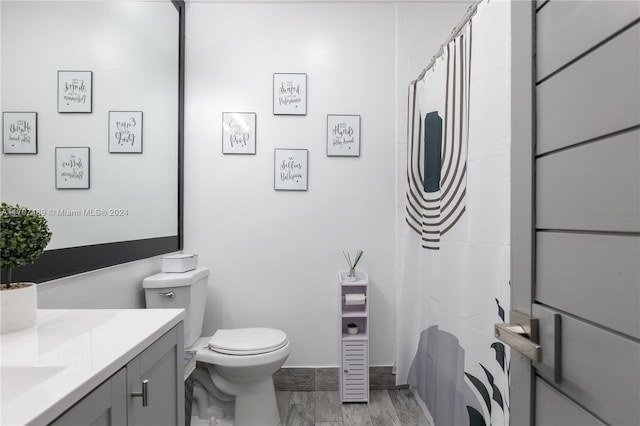 bathroom with hardwood / wood-style flooring, vanity, toilet, and walk in shower