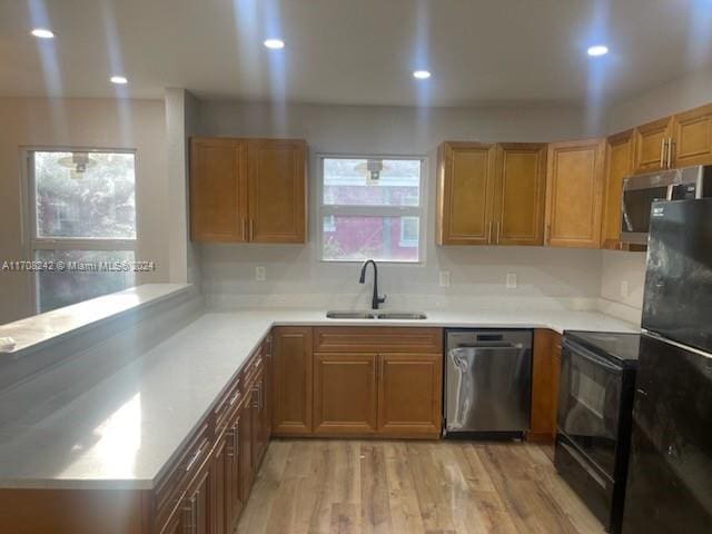 kitchen with sink, black appliances, and light wood-type flooring