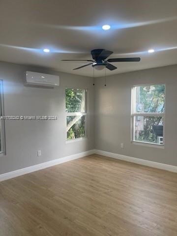 empty room with a wall mounted air conditioner, ceiling fan, and hardwood / wood-style floors