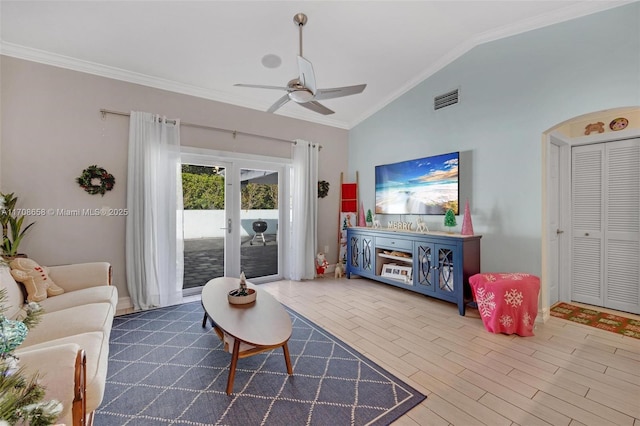 living room featuring vaulted ceiling, hardwood / wood-style floors, ornamental molding, ceiling fan, and french doors