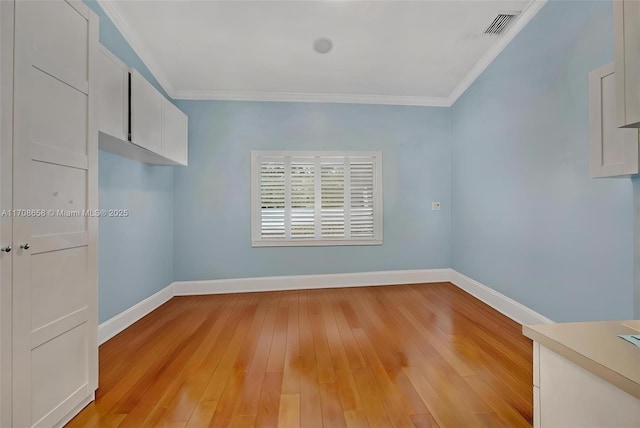 empty room with crown molding and light hardwood / wood-style floors