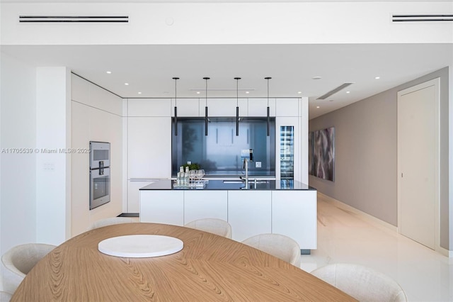 kitchen with white cabinetry, sink, an island with sink, and decorative light fixtures