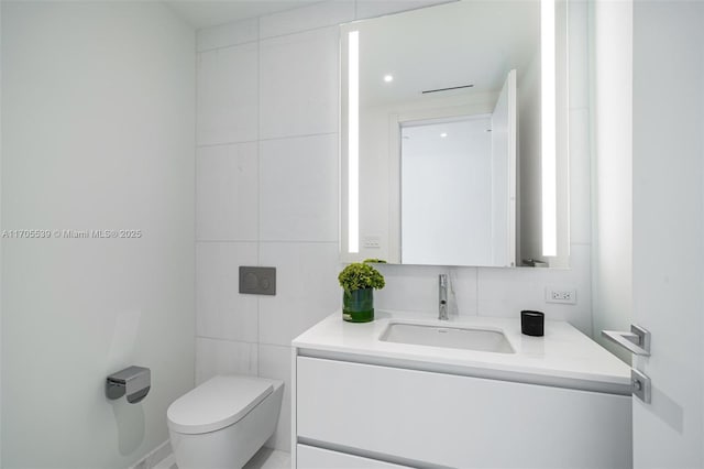 bathroom featuring vanity, tile walls, and toilet