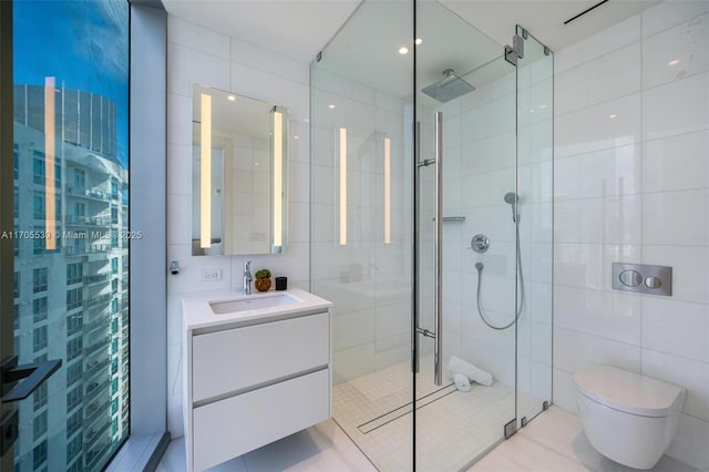 bathroom featuring a shower with door, vanity, tile walls, and toilet