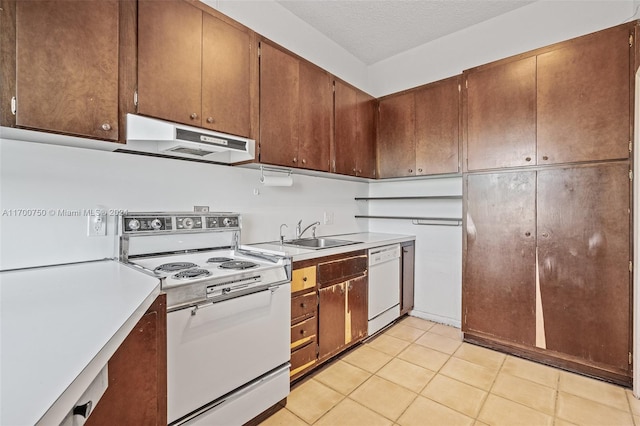 kitchen featuring a textured ceiling, white appliances, sink, and light tile patterned floors