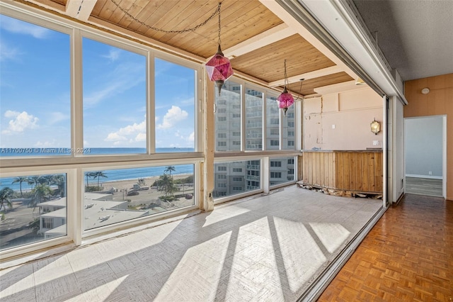 sunroom featuring a water view and wooden ceiling