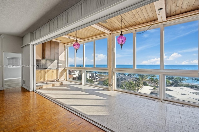 unfurnished sunroom with a water view and wooden ceiling