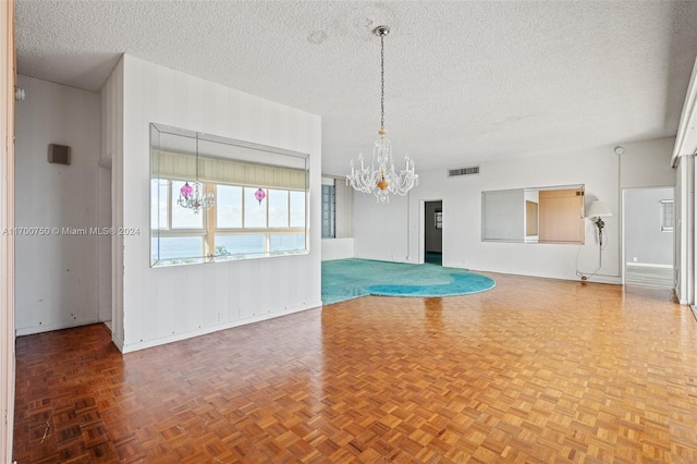 empty room featuring parquet flooring, a textured ceiling, and an inviting chandelier