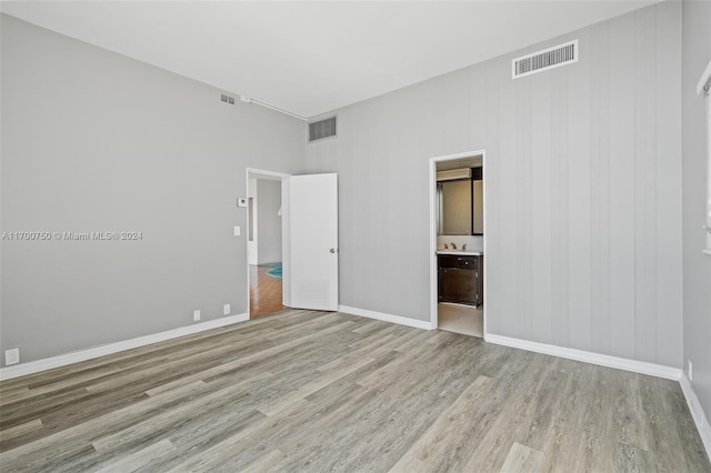 unfurnished bedroom featuring ensuite bath and light hardwood / wood-style flooring