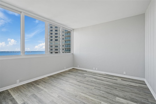 empty room with hardwood / wood-style floors and a water view