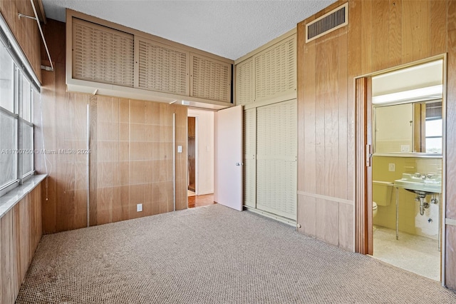 unfurnished bedroom featuring wood walls, a closet, and light carpet