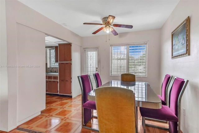 dining space featuring ceiling fan, light tile patterned floors, and sink