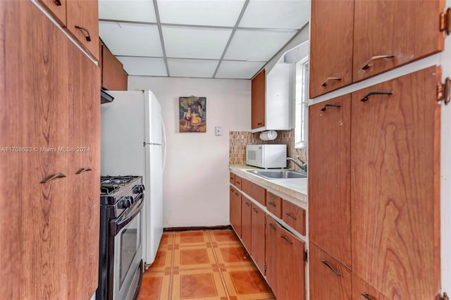 2072 NE 169th St Unit 10, North Miami Beach, FL 33162 - kitchen featuring gas stove, a paneled ceiling, white microwave, light countertops, and tasteful backsplash