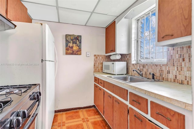 kitchen featuring a paneled ceiling, backsplash, stainless steel range oven, and sink