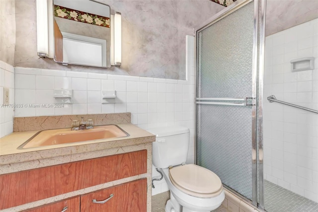 bathroom with walk in shower, vanity, toilet, and tile walls