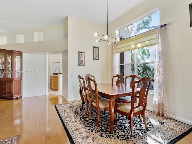 dining space with light hardwood / wood-style floors and an inviting chandelier