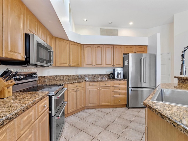 kitchen with sink, light brown cabinets, stainless steel appliances, dark stone countertops, and light tile patterned floors