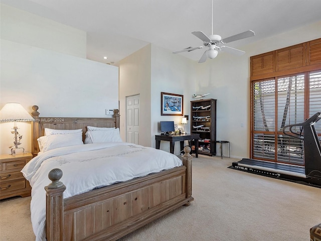 bedroom featuring ceiling fan, light colored carpet, and a high ceiling